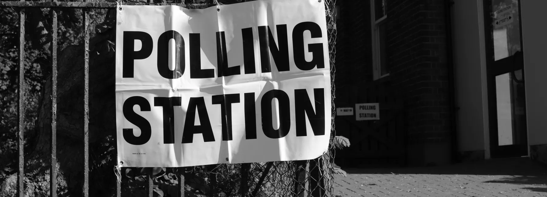 A polling station sign on a fence