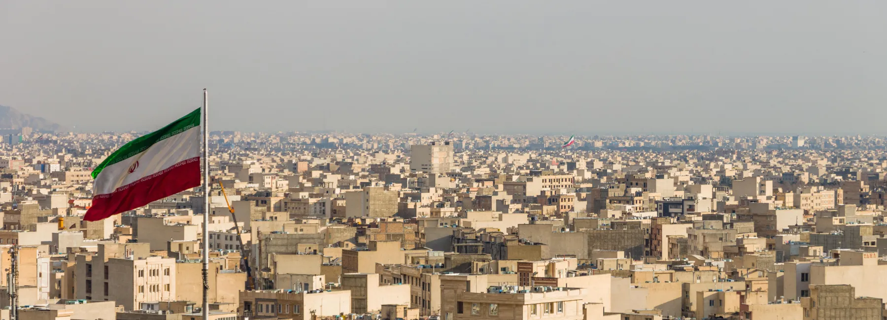 Tehran skyline with Iranian flag in the foreground