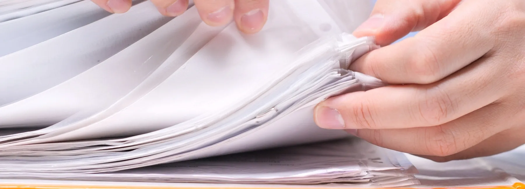Hands leafing through a pile of documents