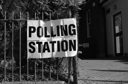 A polling station sign on a fence