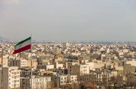 Tehran skyline with Iranian flag in the foreground